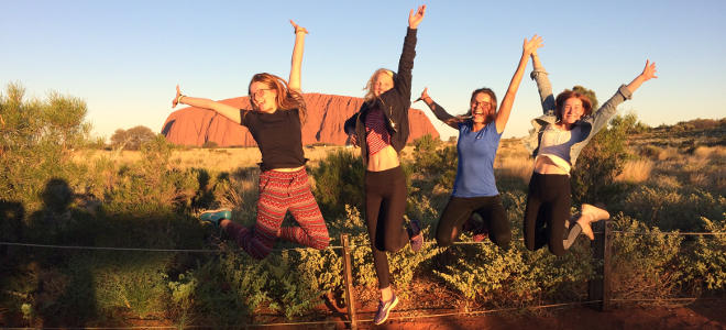 Titelbild Erfahrungsberichte Auslandsjah Australien, Mädchen springen vor Ayers Rock, offiziell „Uluru&quot; in die Luft