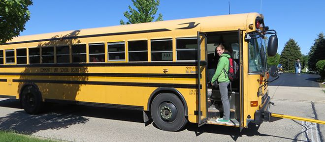 MAP Austauschschülerin in der Tür eines klassisch amerikanischen Schulbusses